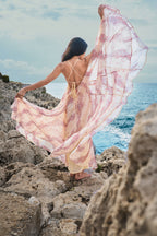 Fließendes, rückenfreies Kleid aus beigefarbenem und rosa Chiffon mit asiatisch inspiriertem Muster der Pariser Marke Phème Paris, fotografiert an der südfranzösischen Küste, ideal für Urlaub, Sommerfeste und Destination Weddings.