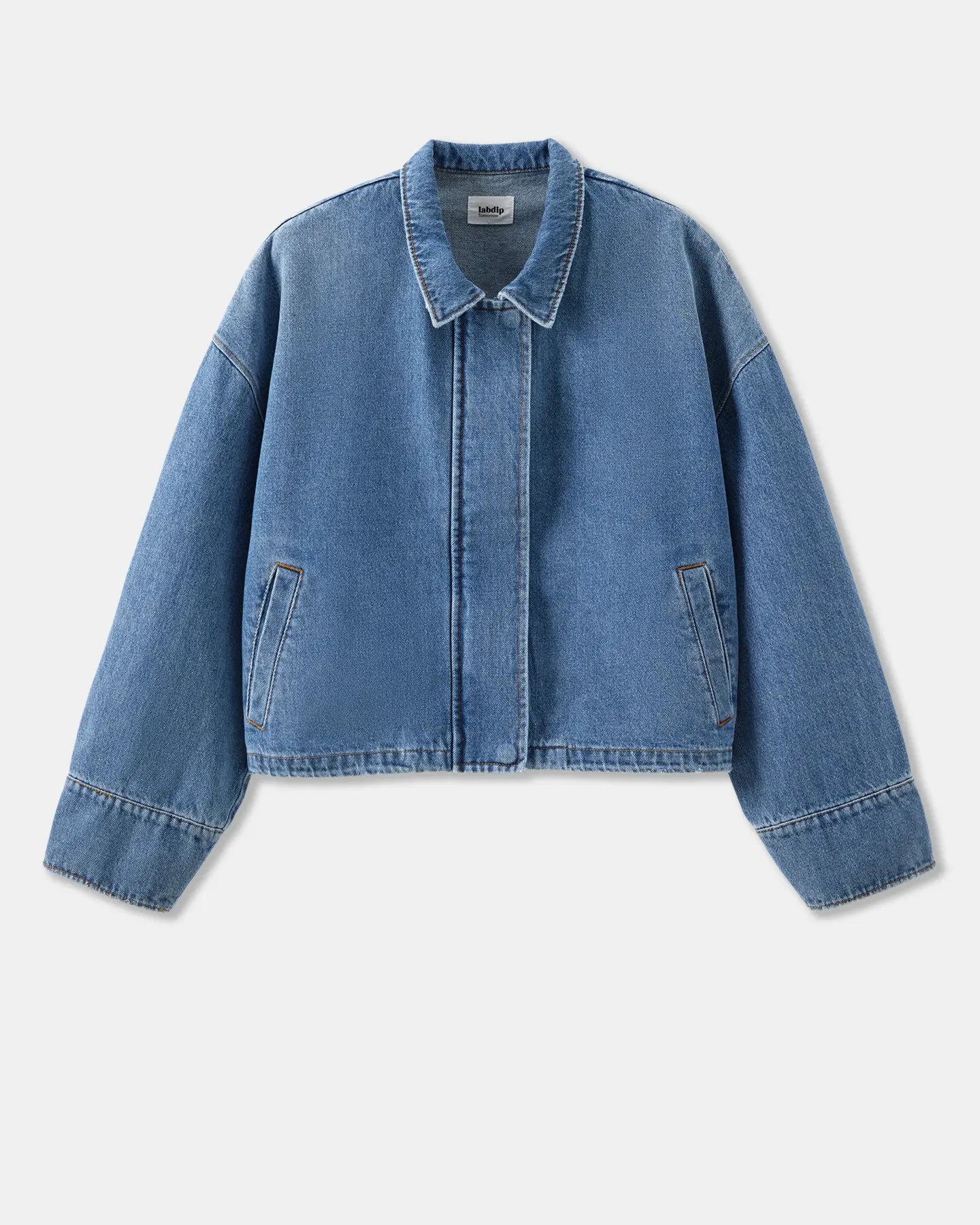 Chaqueta vaquera de algodón de color azul claro, de corte recto y corto con cuello clásico, manga larga ligeramente amplia y discretos bolsillos laterales.