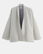 Veste ample en coton léger de couleur granit non teint, avec un col châle et des manches larges, parfaite pour une silhouette décontractée et confortable.