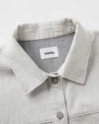 Light granite-colored undyed denim shirt collar with visible stitching and metal buttons, 100% cotton fabric with a structured and natural feel.