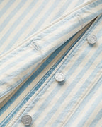 Détail rapproché d’un jean en denim rayé bleu indigo et beige, matière en coton, finition boutons-pression métalliques, coupe ajustée pour femme.