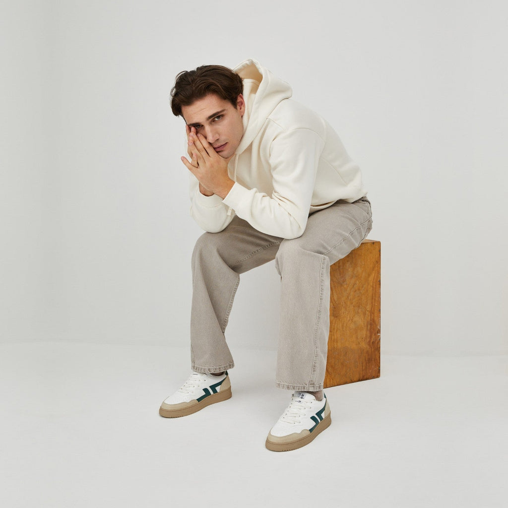 Foto de zapatillas veganas cómodas puestas, con suela gruesa. La zapatilla es blanca con el logotipo verde