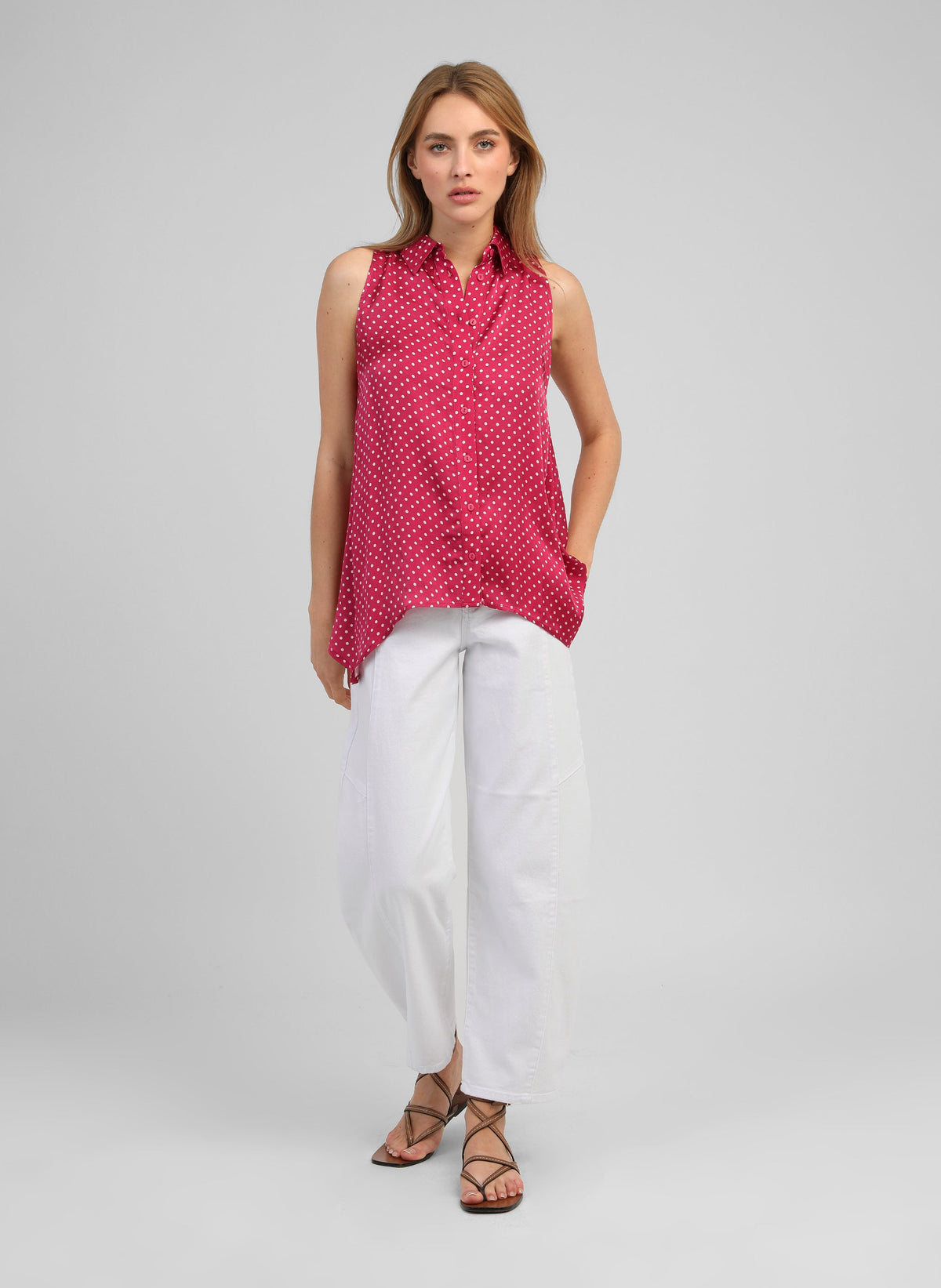 An'ge – Camicia Klarissa Doriva Framboise, modella che indossa una camicetta rosa a pois bianchi e pantaloni bianchi