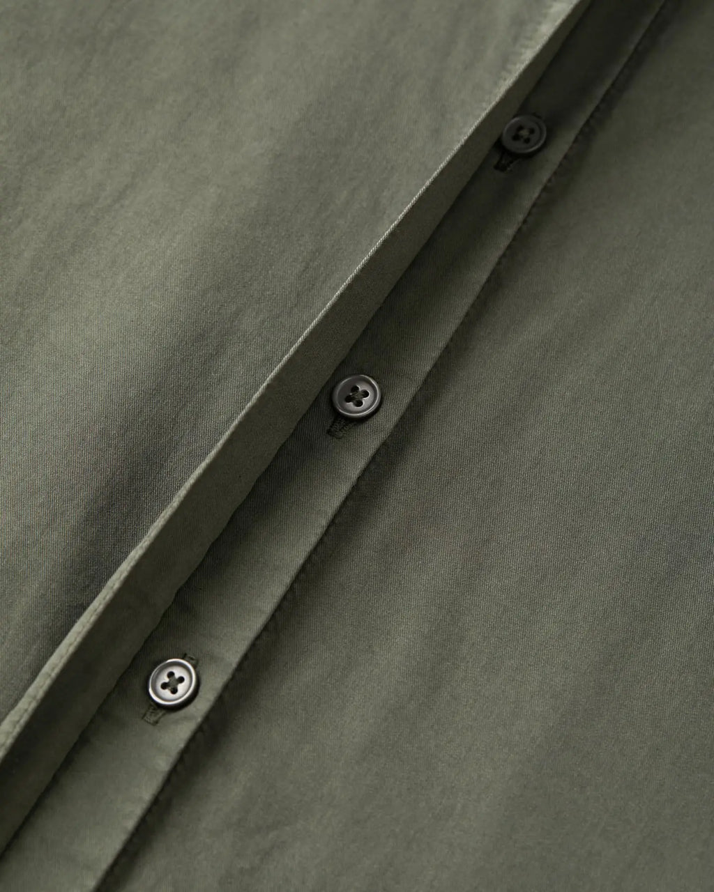 Khaki cotton poplin fabric with sober black buttonholes, showing the quality and finesse of the material, ideal for light and elegant pants.