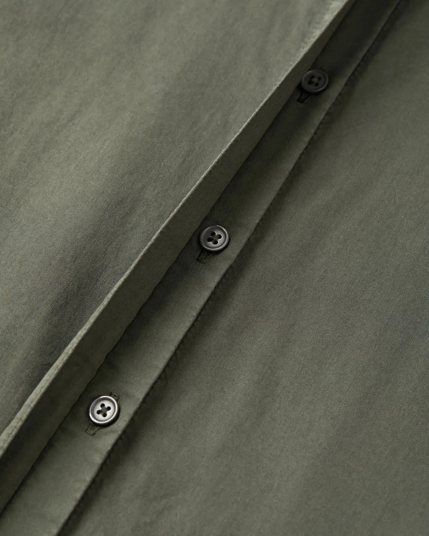 Khaki cotton poplin fabric with sober black buttonholes, showing the quality and finesse of the material, ideal for light and elegant pants.