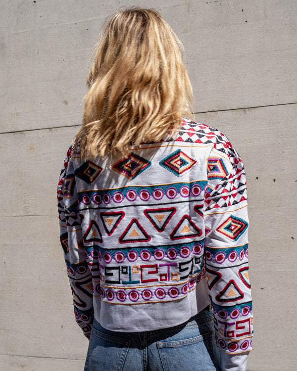 Michonet – Sweat Rombo, kvinde set bagfra iført en hvid sweater broderet med farverige mønstre