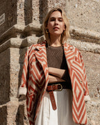 Michonet – Manteau Chevron, mannequin femme blonde portant une veste à motifs géométriques et un pantalon clair