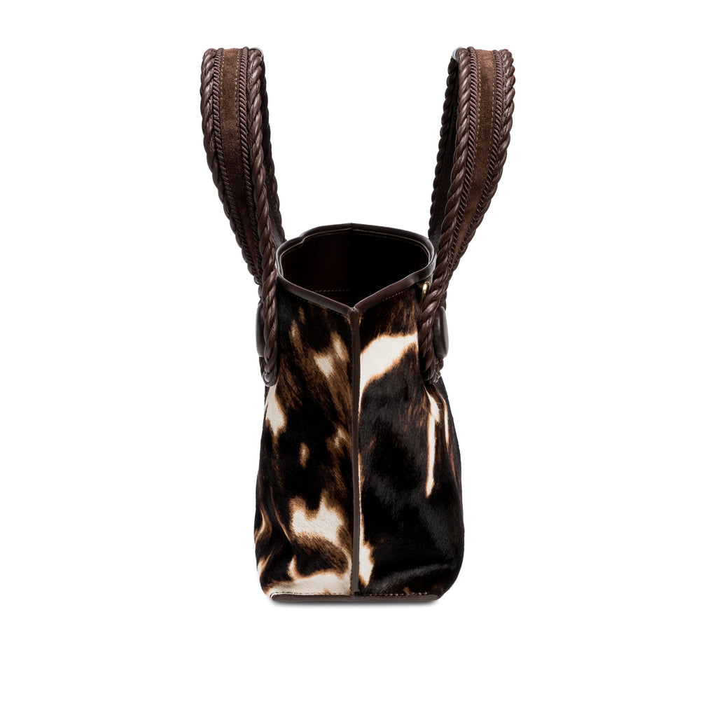 Dark brown and cream cow print pattern small tote bag with open dark brown rope handles on a white background, shown from the side.