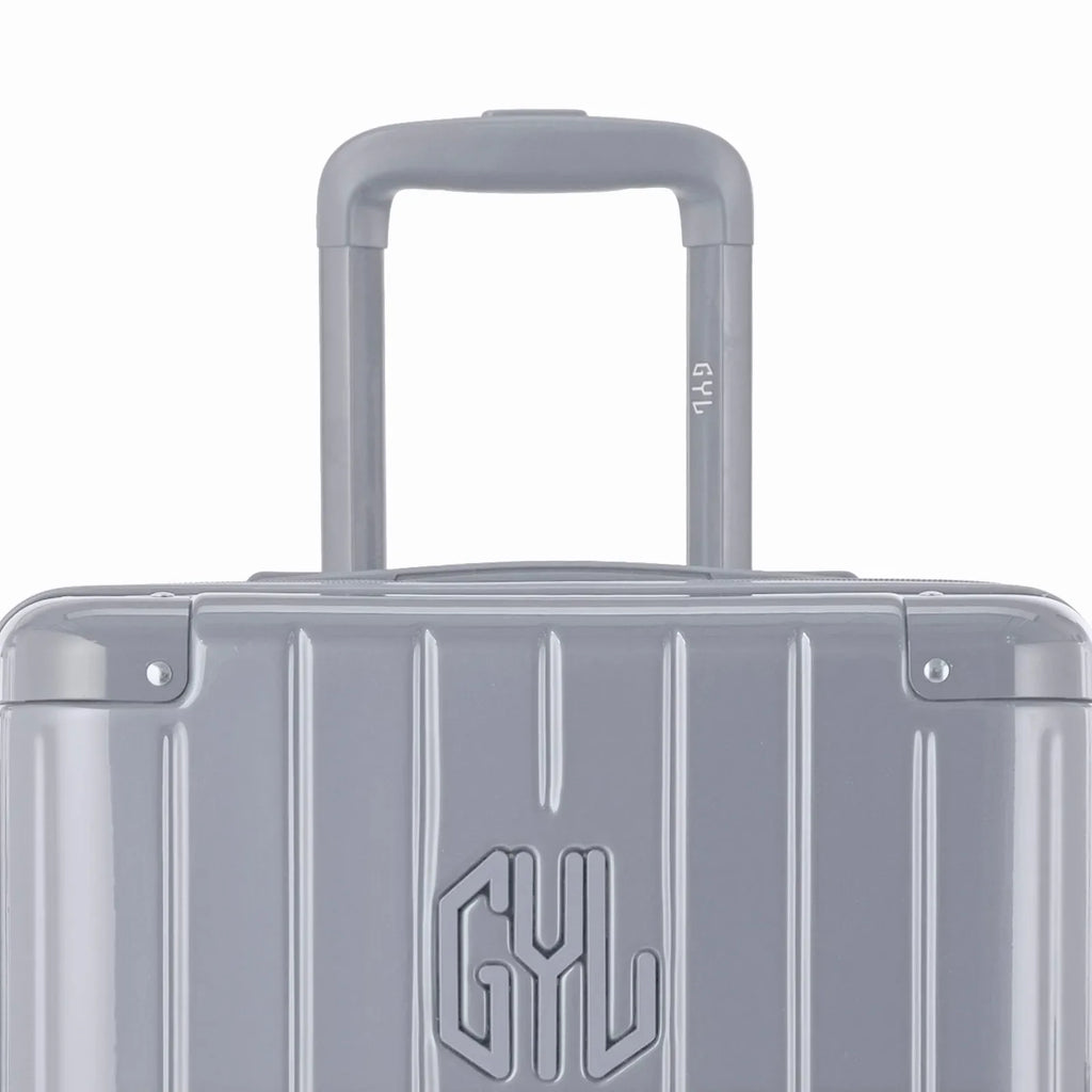 Close-up of the trolley handle and GYL logo on the silver trunk suitcase. #couleur_argent