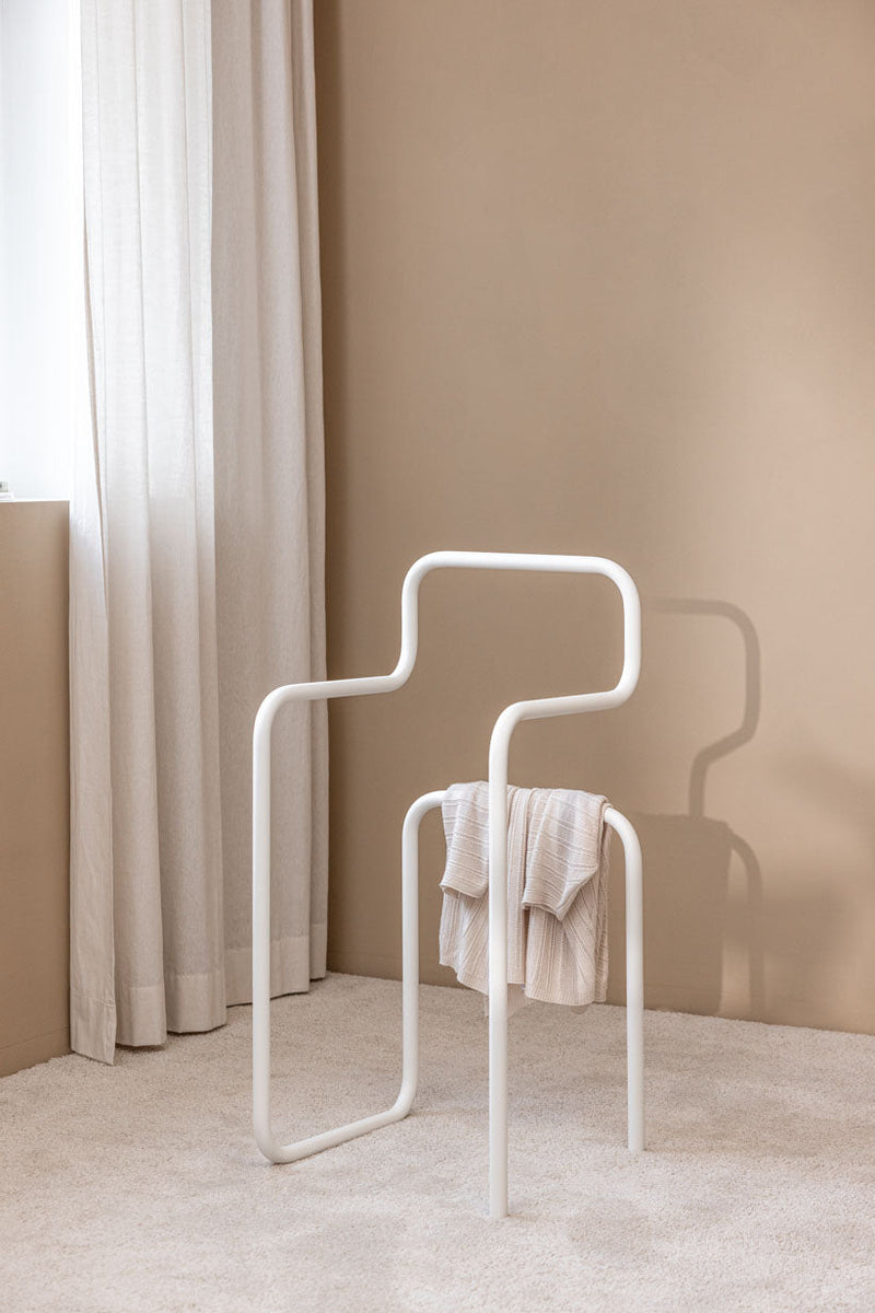 Herrendiener JAMES en forma minimalista con aufgehängtem Kleidungsstück vor einem neutralen Hintergrund.