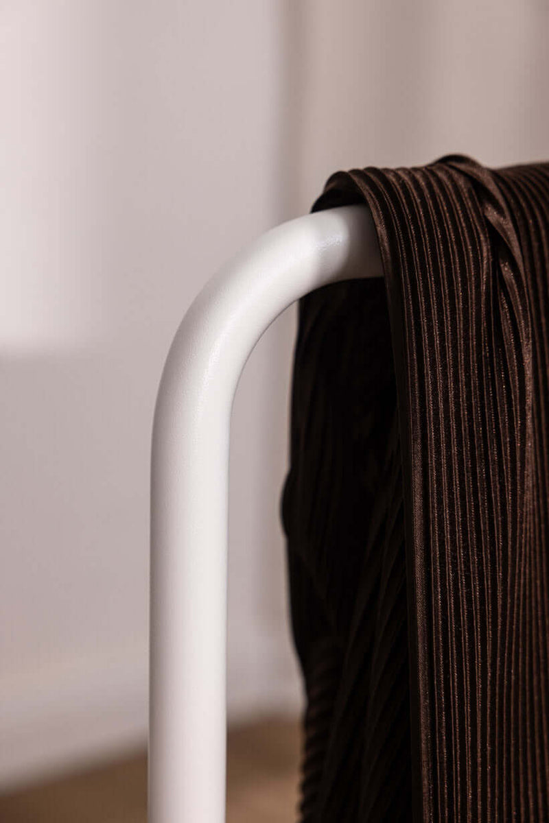 Der Herrendiener zeigt eine Nahaufnahme eines minimalistaischen Kleiderständers mit einem brown Kleidungsstück.
