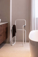 Minimalista Herrendiener JAMES en un moderno Badezimmer mit Kleidung auf dem Ständer.