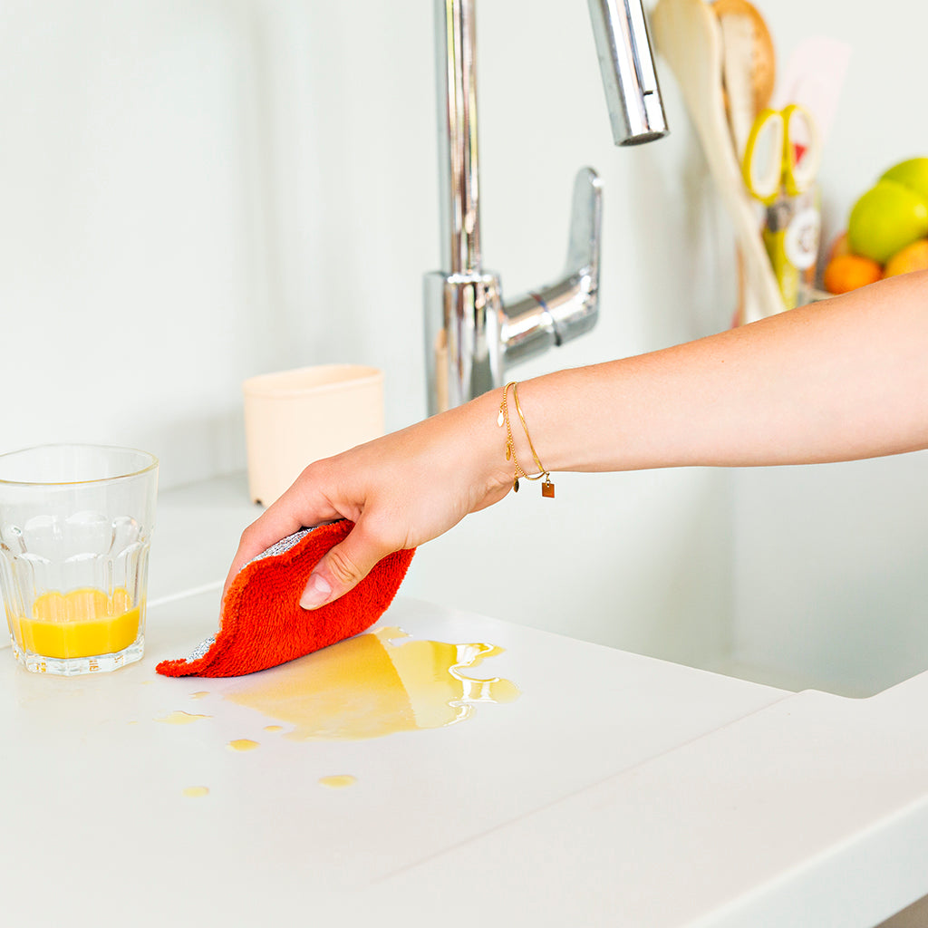 Esponja lavable roja limpiando jugo de naranja 