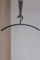 Schwarzer Kleiderbügel FAY hängt an einer Garderobe, minimalistisches Design für moderne Ästhetik.