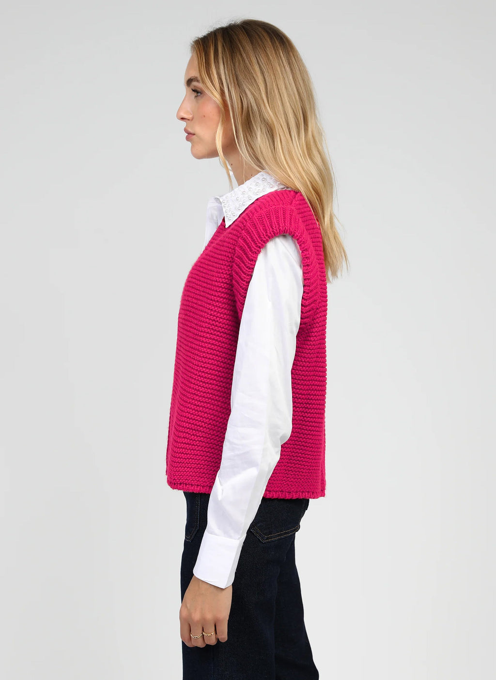 An'ge – Gilet Legringo Fushia, vrouwelijk model in profiel gekleed in een fuchsiazwevende mouwloze trui