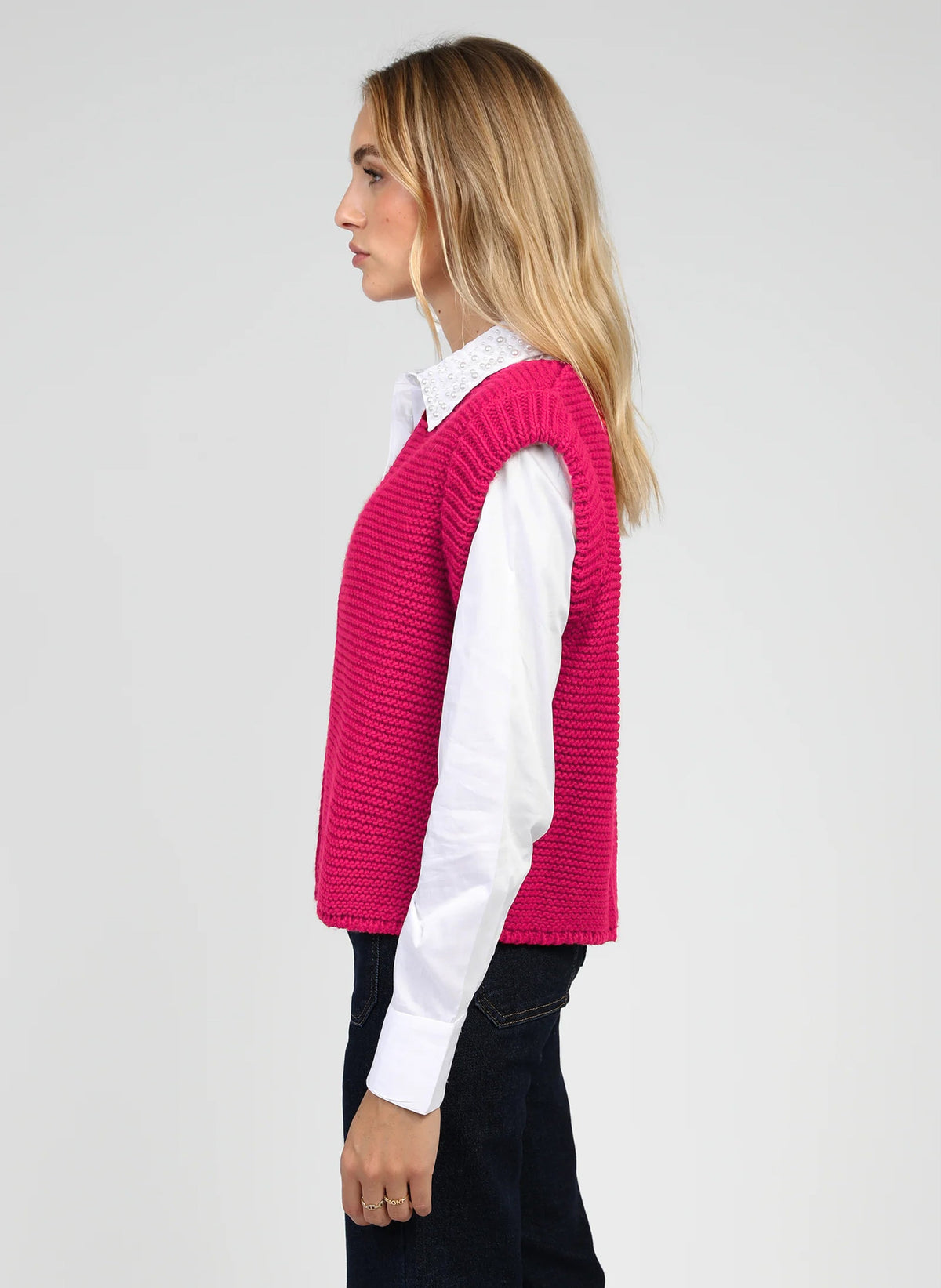 An'ge – Gilet Legringo Fushia, vrouwelijk model in profiel gekleed in een fuchsiazwevende mouwloze trui
