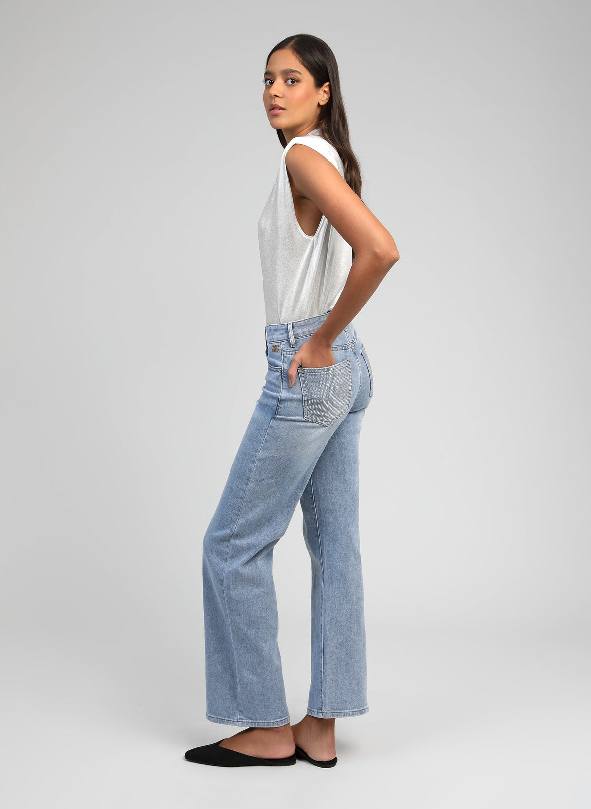 An'ge – Pantalon Pipoche Bleu Ciel, modelka z profilu ubrana w biały top na ramiączkach i jasnoniebieskie jeansy