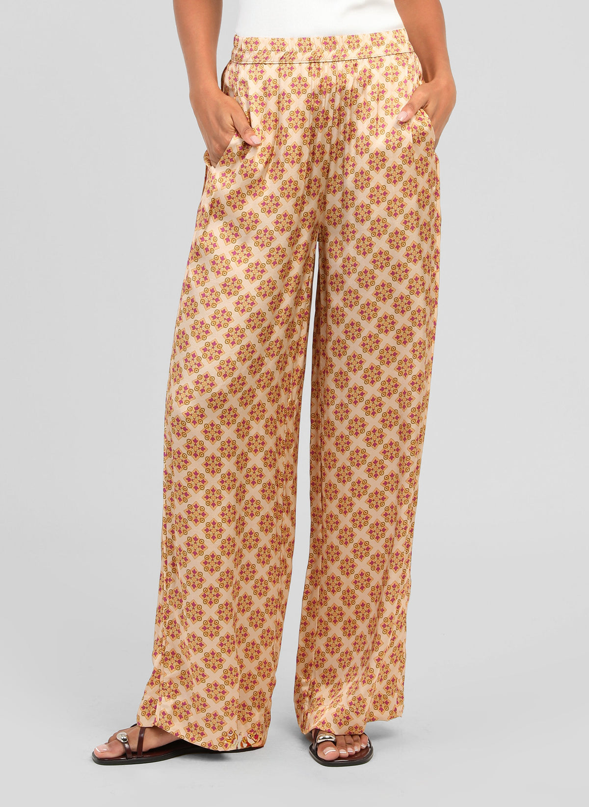 An'ge – Pantalon Presley Pirimini Ble, pantalon fluide beige à motifs géométriques rouges et jaunes, porté de face