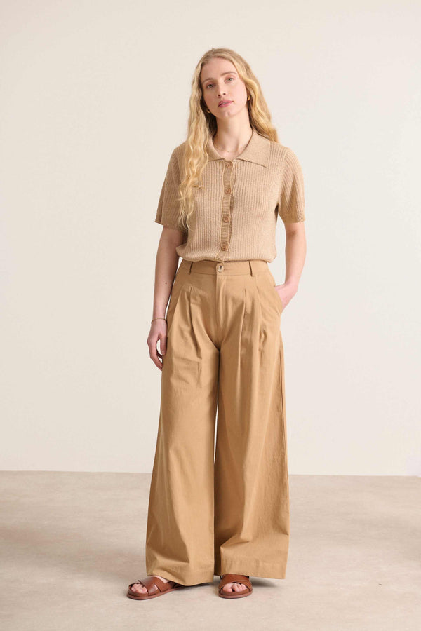 Elegante pantalón beige de pernera ancha y cintura alta con trabillas y detalles de pliegues en la parte delantera. 