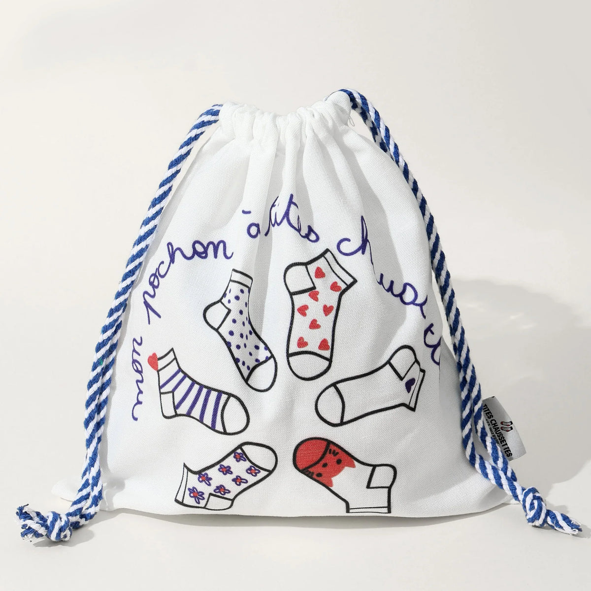 Pochon coton pour ranges ses Tites Chaussettes. Fond blanc, imprimé chaussettes à motifs bleu/rouge. Fermeture par lien coulissant blanc/bleu. 