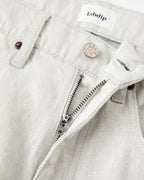 Jean pour femme en denim non teinté couleur granit clair, coupe droite avec fermeture éclair et bouton métal gravé, confection 100% coton avec finition sobre et naturelle.