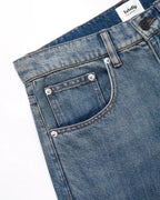 Vaqueros de mujer en denim azul claro desteñido, corte recto con bolsillos clásicos reforzados con remaches metálicos, tejido de algodón grueso y cómodo, ideal para el verano.