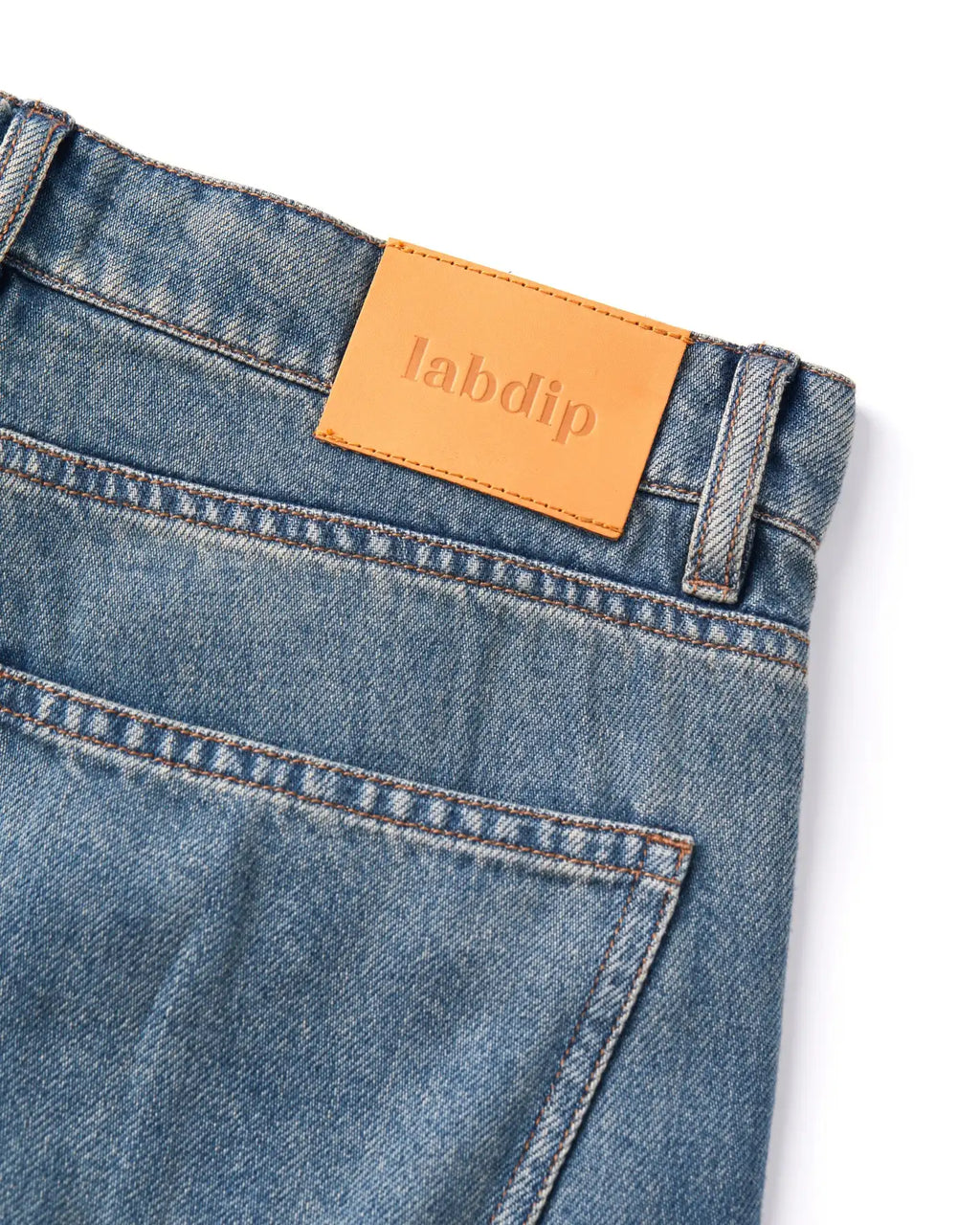 Jeans de denim azul ligeramente desteñido, corte recto clásico con bolsillo trasero, cinturilla reforzada y etiqueta de piel con logo Labdip.