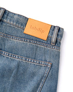 Jeans de denim azul ligeramente desteñido, corte recto clásico con bolsillo trasero, cinturilla reforzada y etiqueta de piel con logo Labdip.