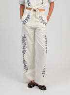 An'ge – Pantalon Rossalie Ecru, pantalon large blanc cassé brodé de motifs végétaux bleus, porté de face