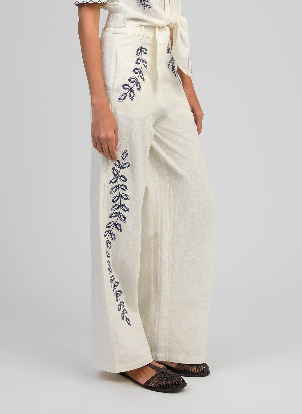 An'ge – Pantalon Rossalie Ecru, pantalon large blanc cassé brodé de motifs végétaux bleus, porté de profil