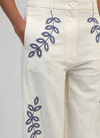 An'ge – Pantalon Rossalie Ecru, pantalon blanc cassé brodé de motifs végétaux bleus, porté par un mannequin