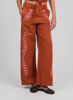 An'ge – Hose Rossalie Caramel, weite braune Hose mit rosa Stickereien, an einem Model getragen