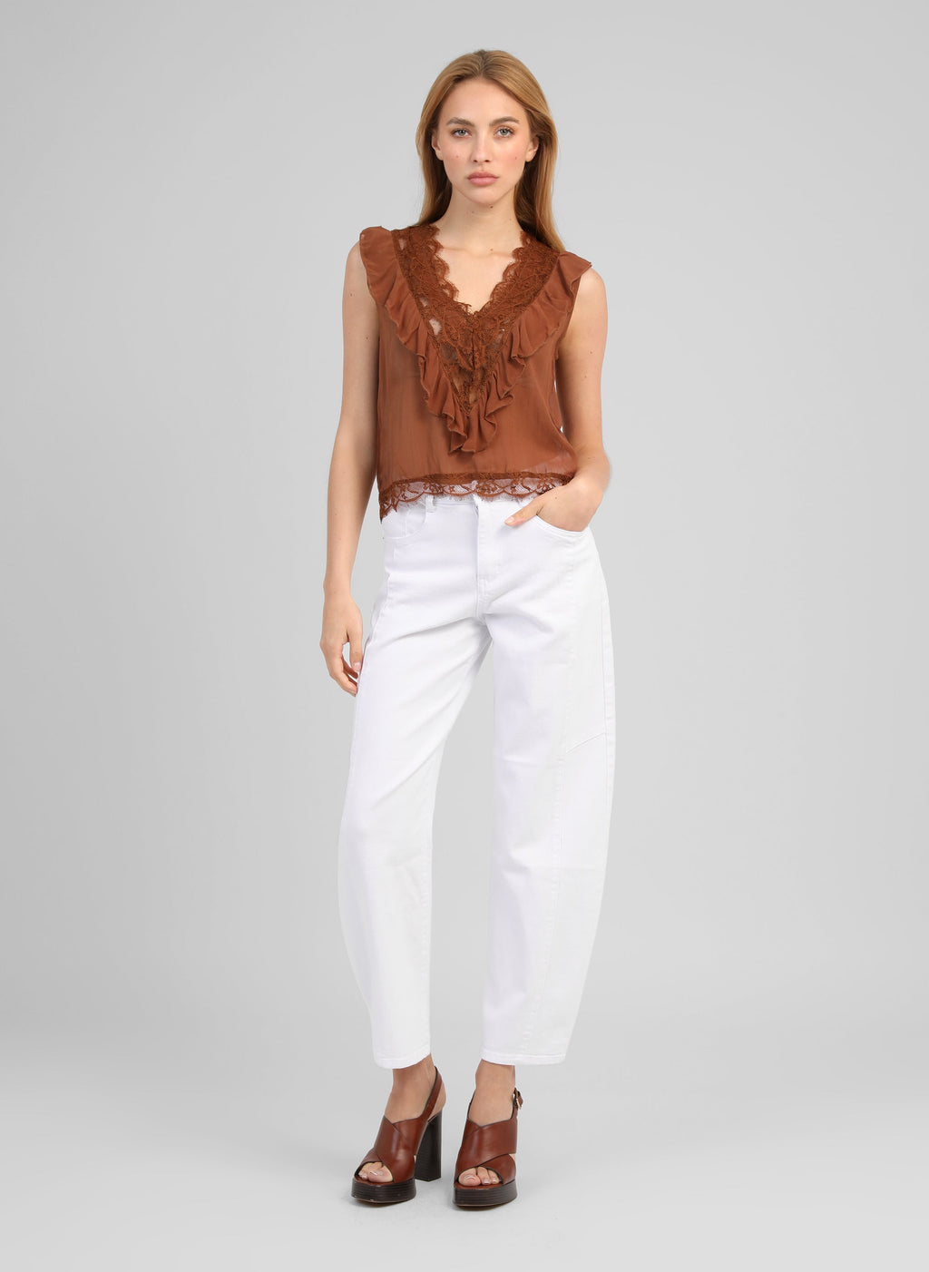 An'ge – Mouwloze top Savilma Bruin, model draagt een bruine top met ruffles en een witte jeans