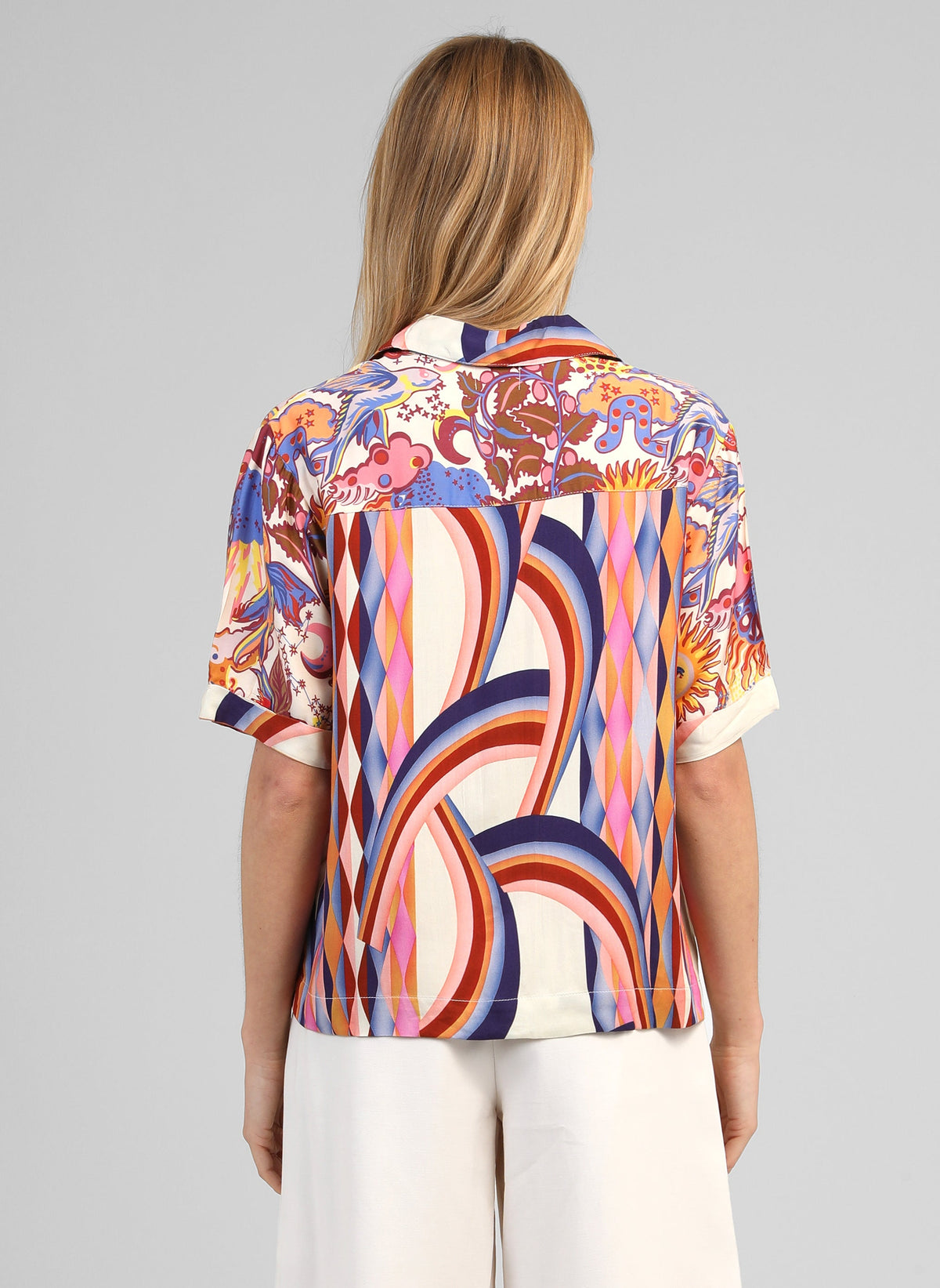 An'ge – Chemise Shanone Solemio, model van achteren gezien in een overhemd met kleurrijk motief en een witte broek