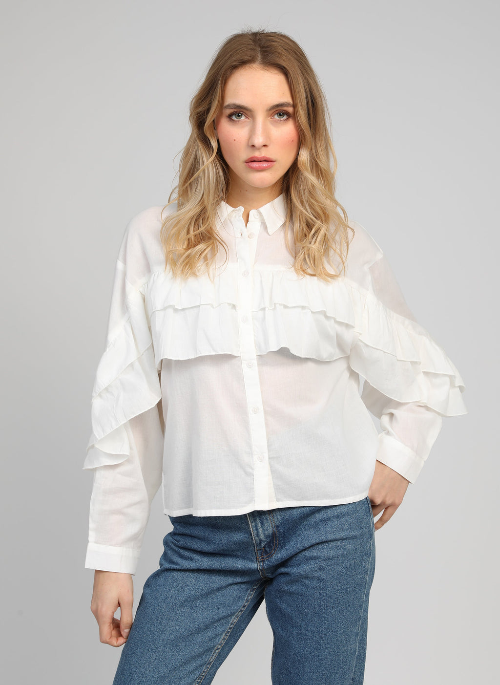 An'ge – Camicia Suprema Blanc, modella che indossa una camicia bianca con volant e jeans blu, vista frontale