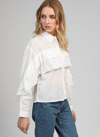 An'ge – Camicia Suprema Blanc, modella che indossa una camicia bianca con volant e jeans blu