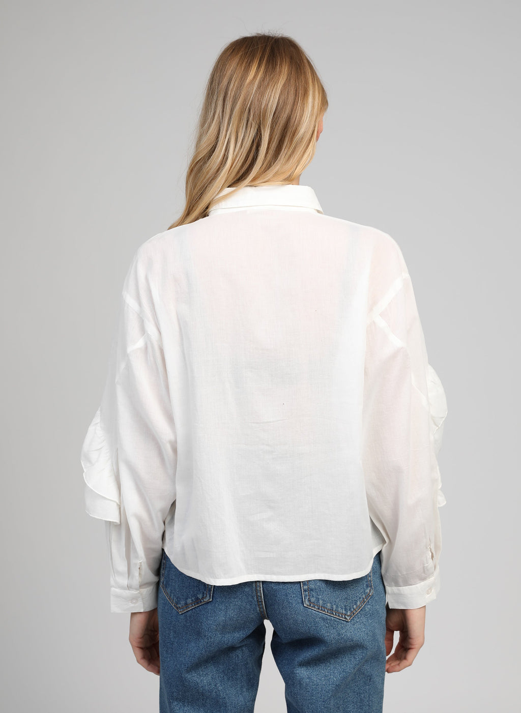 An'ge – Camicia Suprema Blanc, modella di spalle che indossa una camicia bianca in cotone e jeans blu