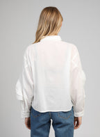 An'ge – Camicia Suprema Blanc, modella di spalle che indossa una camicia bianca in cotone e jeans blu