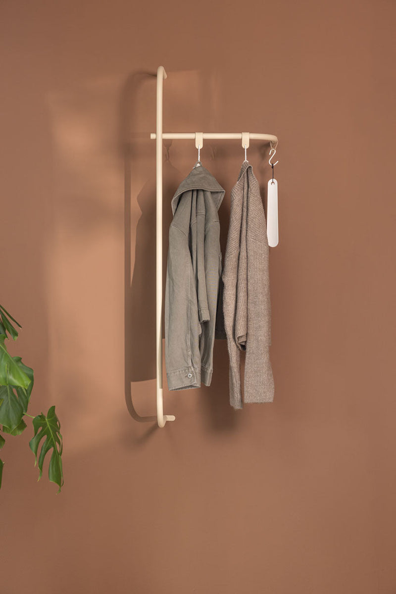 Armario TAMINA con materiales metálicos minimalistas y colgantes Kleidungsstücken con una varita marrón.