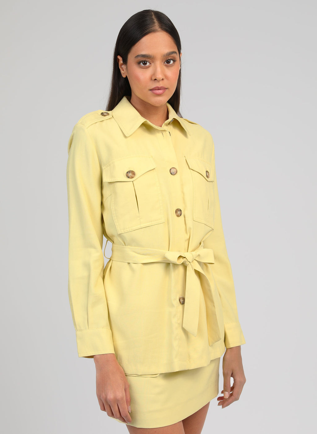 An'ge – Giacca Zoana Paille, modella che indossa una giacca camicia giallo chiaro con cintura e gonna