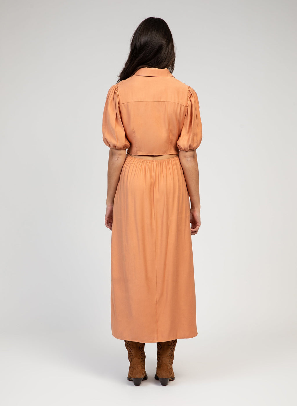 An'ge – Malida Maxi Dress Terracotta, back view of model wearing an orange maxi dress in a flowing fabric