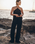 Woman in a black outfit standing on rocky terrain with water in the background