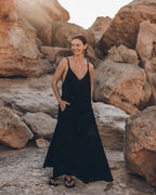 Woman in a black dress standing among large rocks.