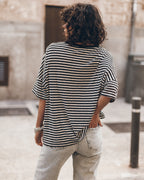 Woman wearing a striped t-shirt and light jeans standing on a street.