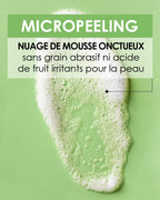 Close-up on the texture of Pschitt Magique Garancia: a cloud of creamy white foam on a green background, with text specifying a formula without abrasive grain or irritating fruit acid.