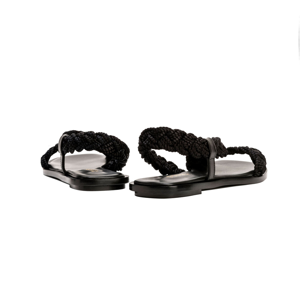 Ronda Black Flat Asymmetric Sandal with braided straps and sleek black leather sole, perfect for summer adventures.